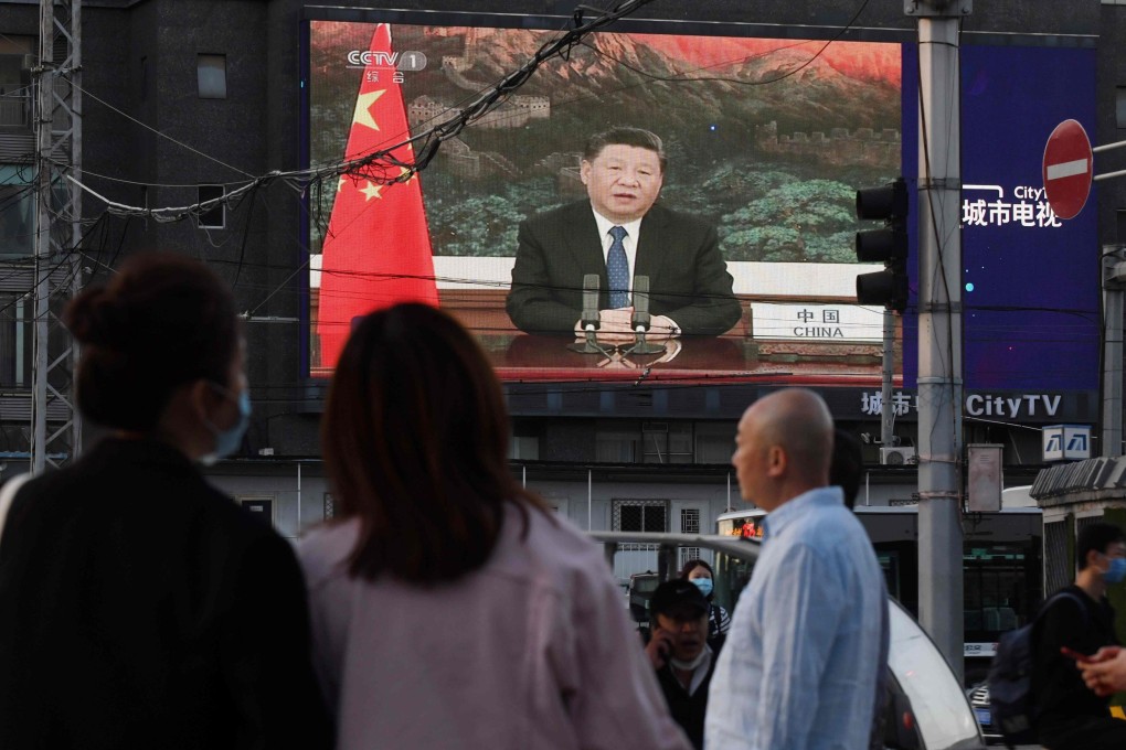 People watch footage of Chinese President Xi Jinping speaking at the World Health Assembly on a giant screen in a Beijing street on Monday. Photo: AFP