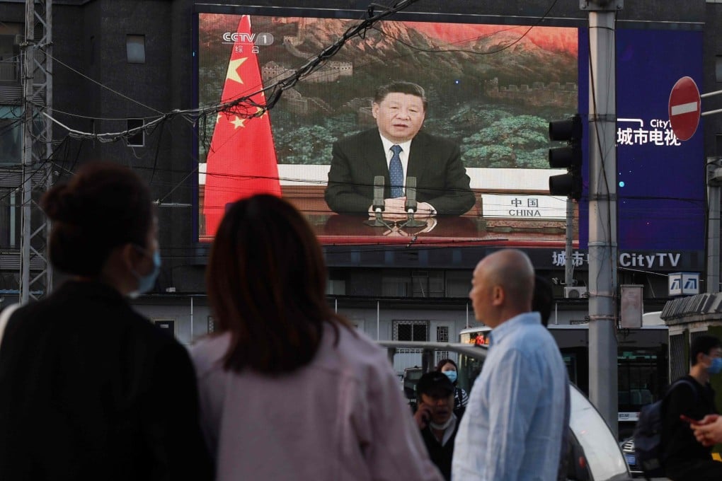 People watch footage of Chinese President Xi Jinping speaking at the World Health Assembly on a giant screen in a Beijing street on Monday. Photo: AFP