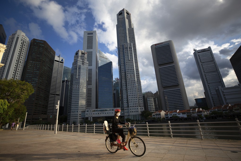 A cyclist wearing a protective face mask rides in front of the Central Business District area in Singapore, Photo: EPA-EFE