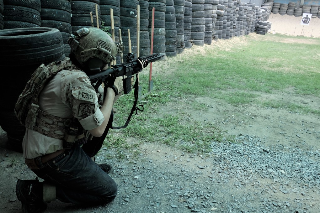 Sutipatt Sudhisanronakorn, a gun enthusiast who works as a flight attendant, fires at a target with a military assault rife while dressed as a US Navy Seal commando at a shooting range outside Bangkok, Thailand. Photo: Tibor Krausz