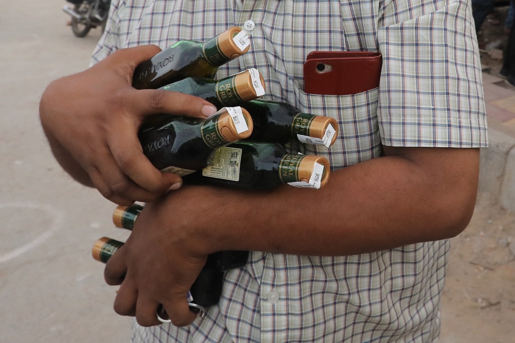A man buys numerous bottles of liquor after India relaxed restrictions on the sale of alcohol earlier in May, amid concerns about the financial impact of lost revenue. But increased alcohol consumption has led to a rise in domestic abuse, women’s groups say. Photo: EPA-EFE