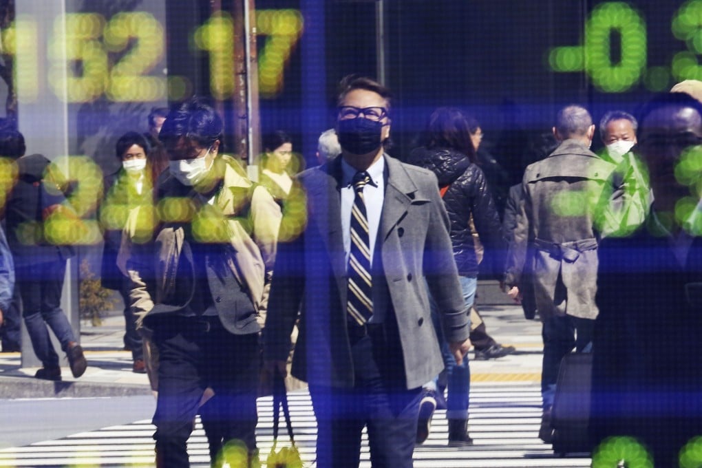 People are reflected on the electronic board of a securities firm in Tokyo. Photo: AP