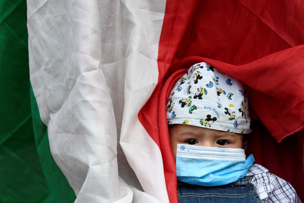 A child wearing a face mask is seen next to an Italian flag in Milan on Monday. Photo: Reuters