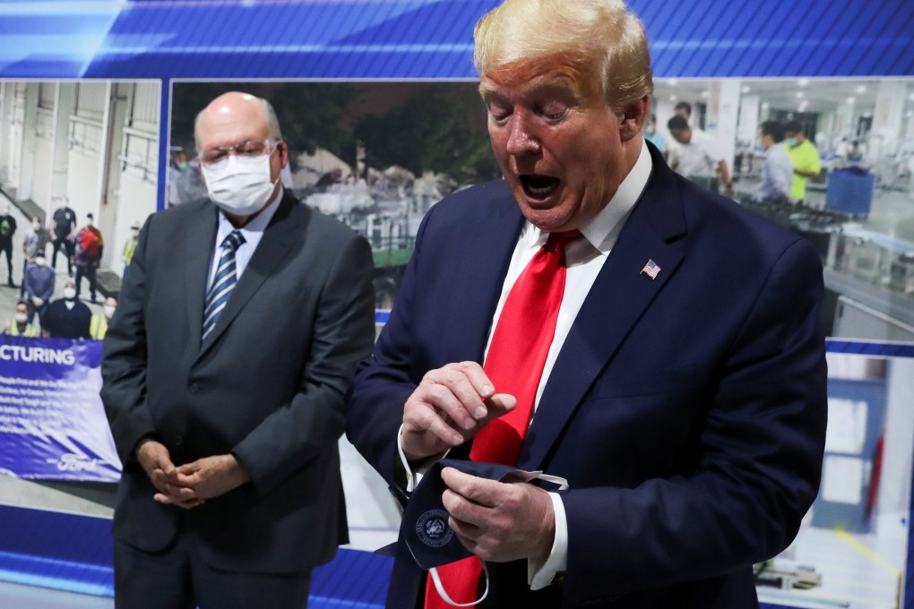 US President Donald Trump holds a face mask he says he wore earlier as Ford CEO Jim Hackett looks on during at the company’s factory in Michigan on Thursday. Photo: Reuters