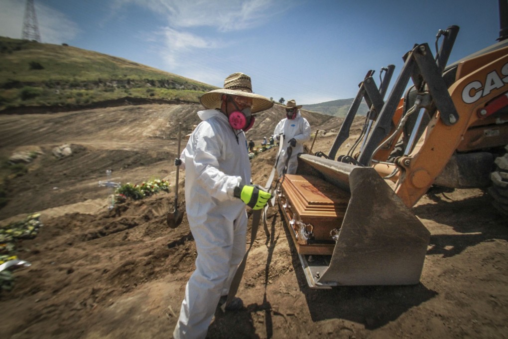 Workers in full protection gear unload a coffin that contain the remains of a person who died from the new coronavirus, in an area of the municipal cemetery set apart for victims of Covid-19, in Tijuana, Mexico. Photo: AP Photo