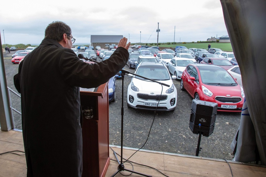 Pastor Billy Jones stands inside a potato delivery lorry as he delivers his sermon to his parishioners. Photo: AFP