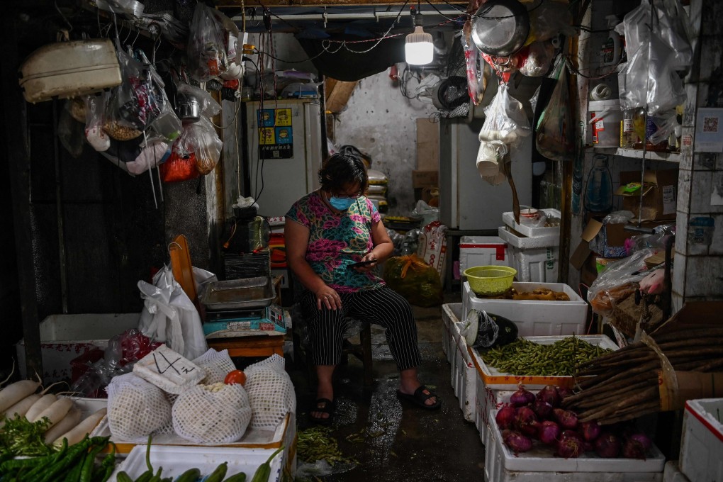 A vendor wearing a face mask sits in her shop in Wuhan, in China’s central Hubei province. Photo: AFP