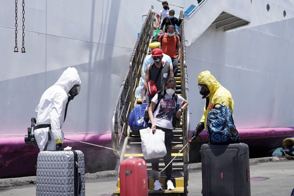 Government workers spray disinfectant on the luggage of disembarking overseas Filipino workers at a seaport in Cebu City on Saturday. Photo: EPA