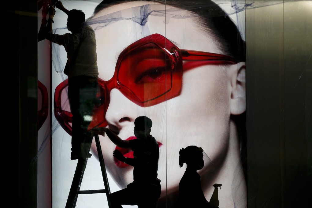 Workers install an advertisement for a luxury fashion brand at Siam Paragon shopping complex in Bangkok, Thailand. Photo: EPA