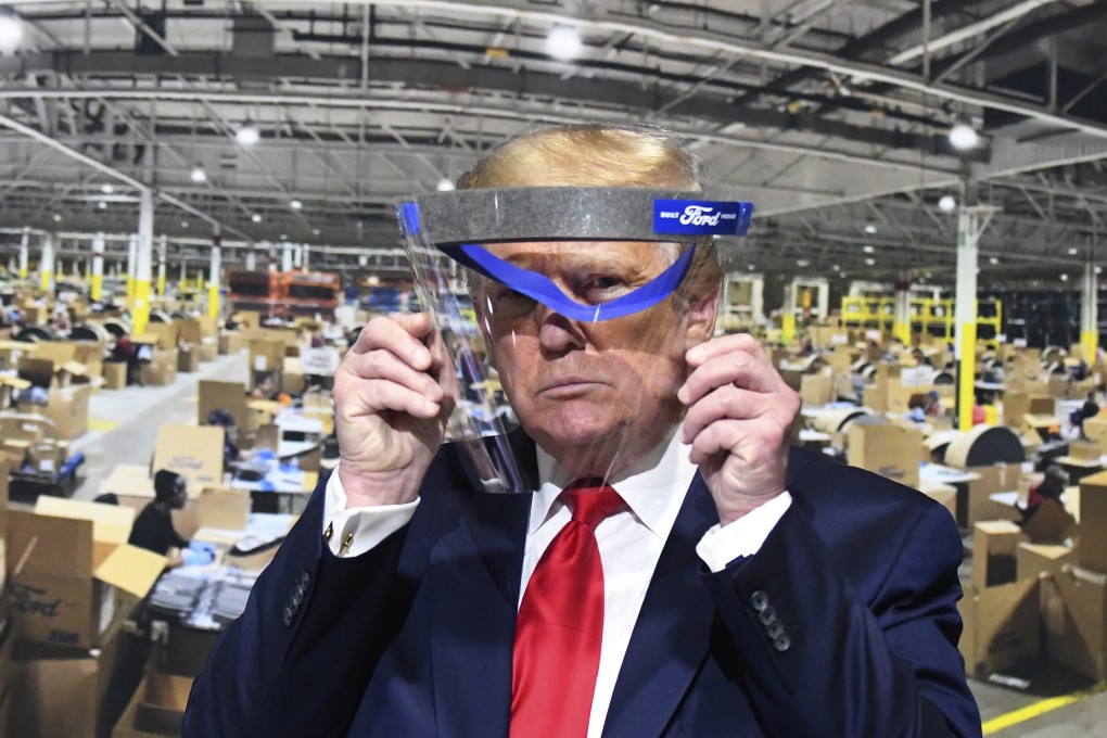 US President Donald Trump looks through a face shield, in front of a poster showing the manufacturing of the shields, while touring Ford's Rawsonville Components Plant in Ypsilanti, Michigan, on May 21. Photo: AP