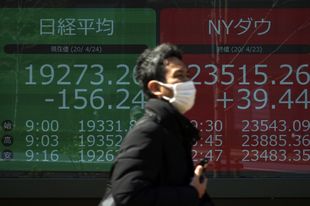 A man wearing a mask twalks past an electronic stock board showing Japan's Nikkei 225 and New York Dow indexes at a securities firm in Tokyo. Stocks in Asia-Pacific region are rising on the back of measures to reboot economies. Photo: AP