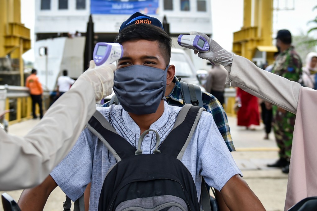Health officers check the body temperature of a passenger disembarking a ferry. Photo: AFP