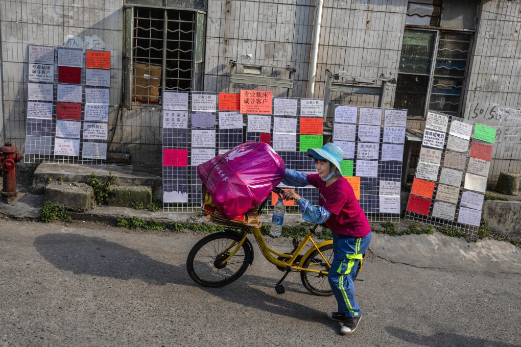 A woman walks by a message boards filled with ads for jobs, flats to rent and business services in Little Hubei village of Guangzhou, Guangdong province. Photo: EPA-EFE