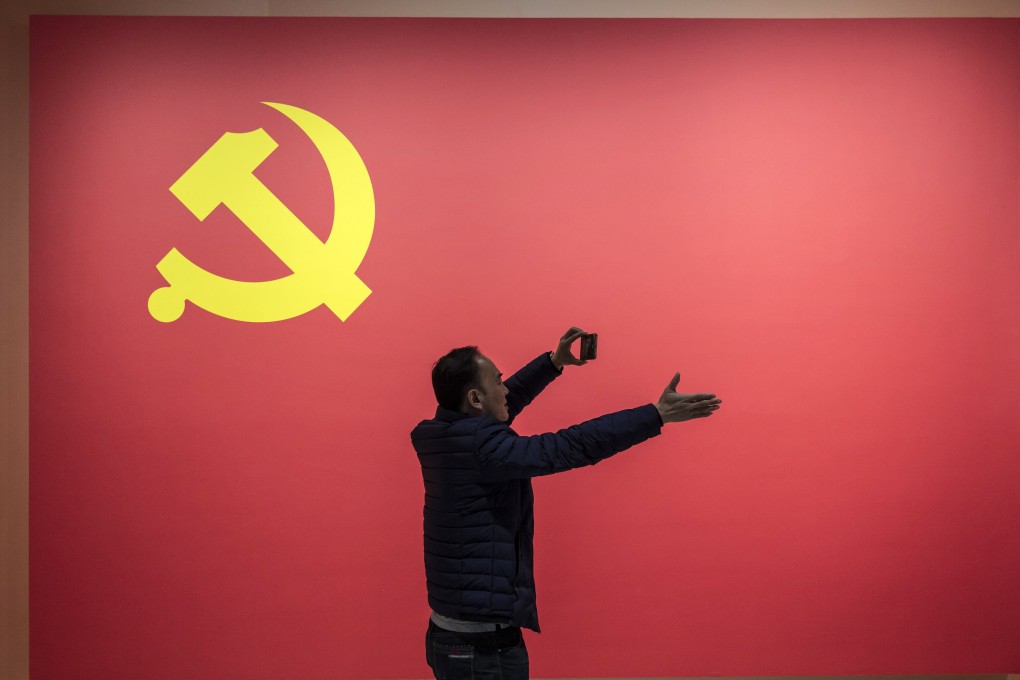 A man uses a smartphone in front of the Chinese Communist Party flag. YouTube said it was investigating the removal of comments critical of China’s ruling party from the video-sharing platform. Photo: Bloomberg