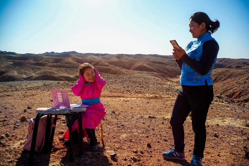 Ce Geng (left) prepares to take an online class as her mother looks on in Alxa Left Banner, in north China’s Inner Mongolia Autonomous Region, on April 1. The nine-year-old’s parents drive her around their ranch to look for better Wi-fi when the weather is bad so she can attend classes online after schools shut due to Covid-19. Photo: Xinhua