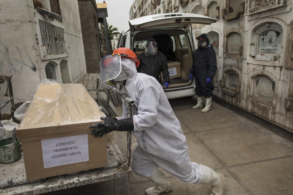 A cemetery worker in a hazmat suit moves a Covid-10 victim’s coffin at El Angel cemetery, in Lima, Peru on Monday. Photo: AP