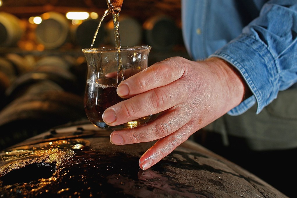 A worker at Bruichladdich distillery takes a whisky sample from a cask. Photo: Getty Images