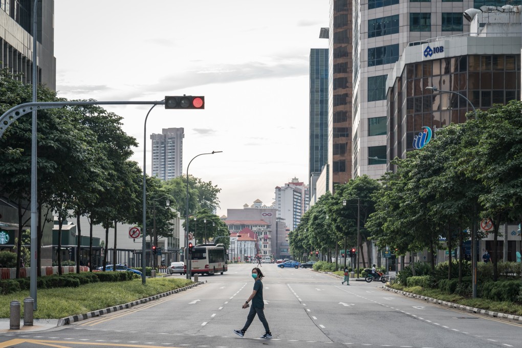 A pedestrian wearing a mask crosses a near-empty street in the central business district during the “circuit breaker” lockdown in Singapore on May 20. Singapore will allow more businesses to reopen on June 2 after a nationwide lockdown cut transmission of the coronavirus among citizens and permanent residents. Photo: Bloomberg