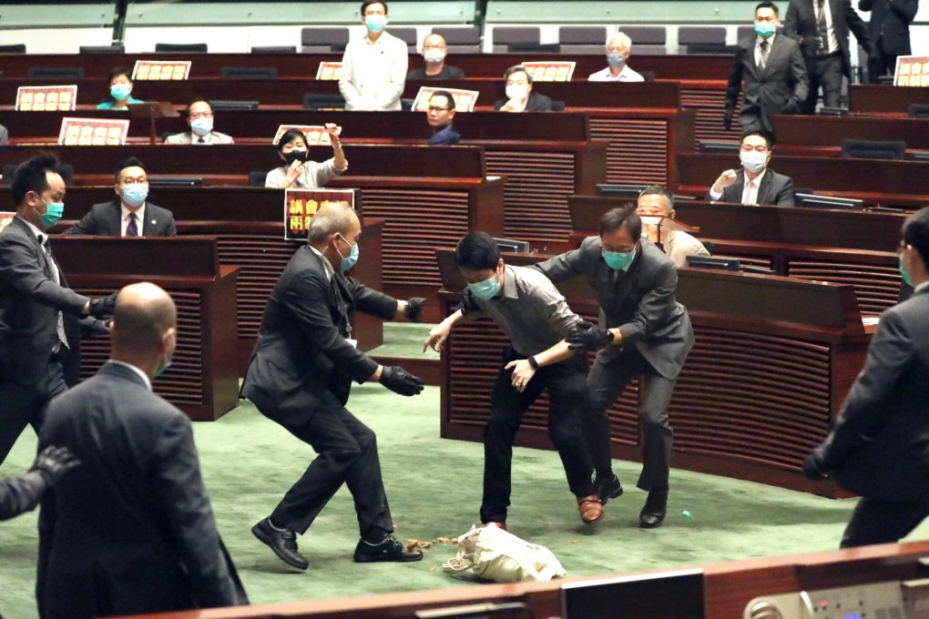 Lawmaker Ted Hui is stopped by security guards as he attempts to throw a container of rotten plants at Legislative Council president Andrew Leung. Photo: Nora Tam