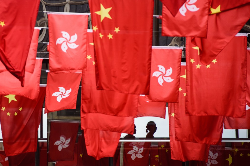 People walk along a passageway connecting two buildings festooned with Hong Kong and Chinese flags on June 27, 2017, as part of preparations to mark the 20th anniversary of the city’s handover from Britain to China on July 1. Photo: AFP