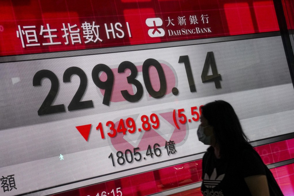 A woman walks past an electronic board displaying the Hang Seng Index in Central on May 22. Recent developments have cast a dark shadow over Hong Kong. Photo: Felix Wong