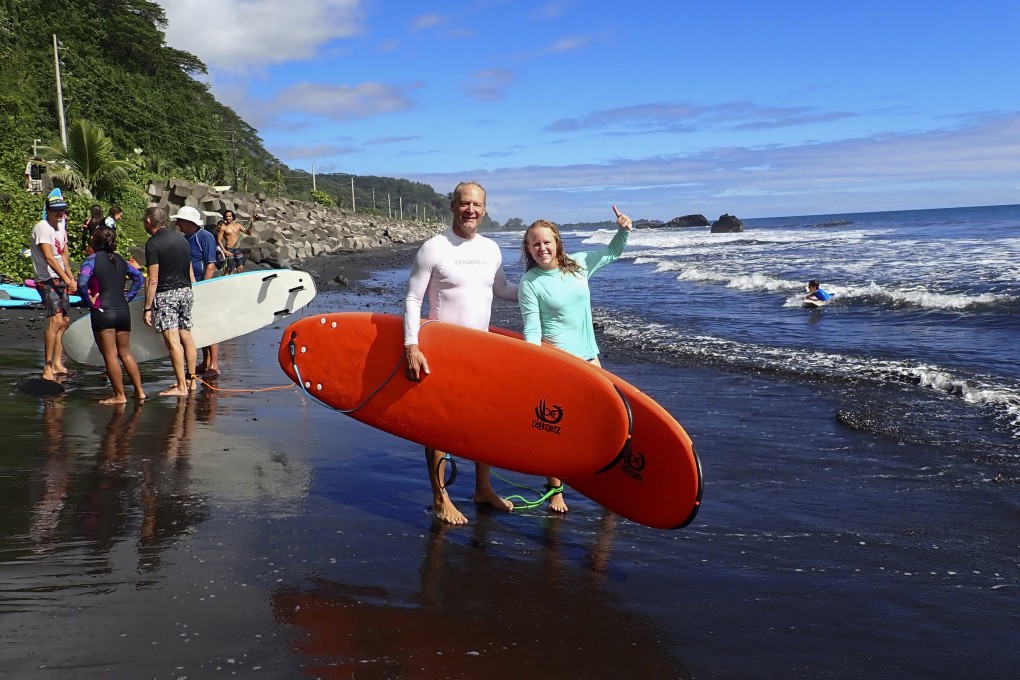 Kristen Pankratz, right, and her father David pose with their boards before going surfing in Tahiti. They are stuck in the South Pacific as the coronavirus pandemic restricts travel and countries close their borders. Photo: AP