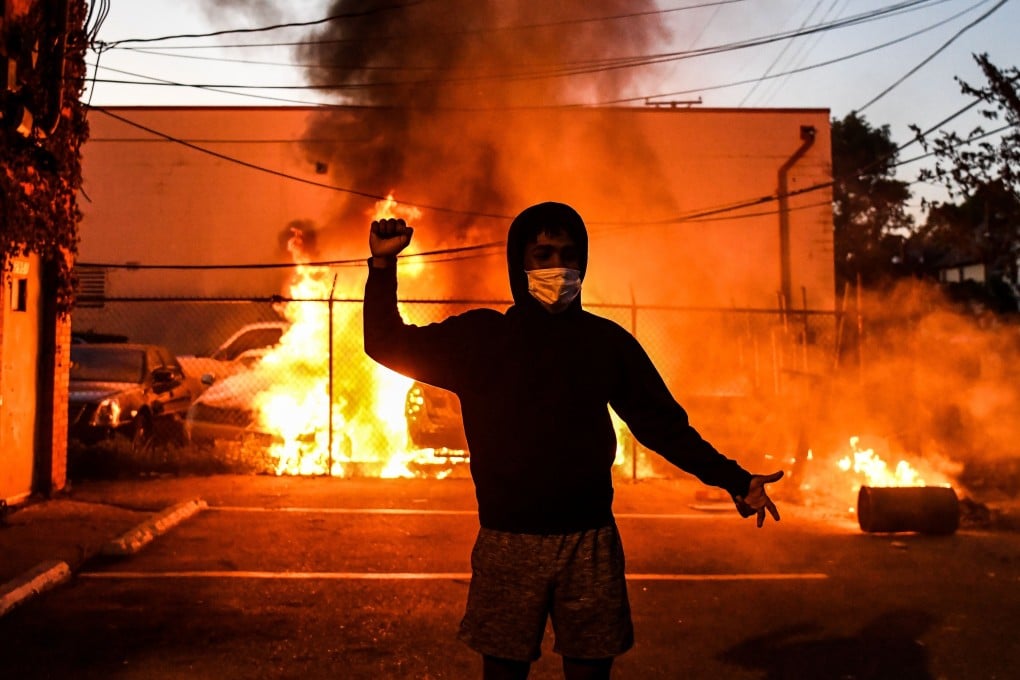 A protester gestures as cars burn behind him as violence continues to erupt following the death of George Floyd, a unarmed black man who died after a white policeman knelt on his neck for several minutes. Photo: AFP