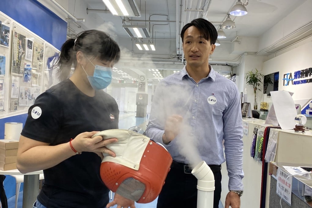 Salom Yiu Kam-shing demonstrates how his disinfection product sterilises a mask with fencer Alison Yu Chui-yee. Photo: Chan Kin-wa