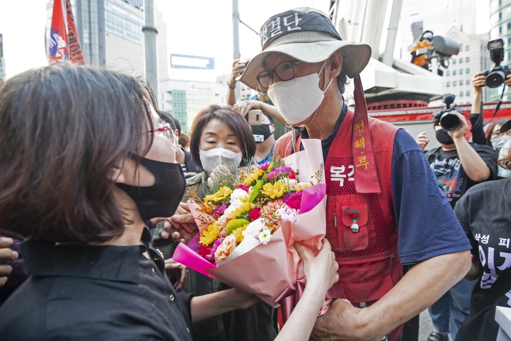 Former Samsung employee Kim Yong-hee receives a bouquet of flowers after coming down from on top of a 25 metre traffic camera tower in Seoul after a year-long protest. Photo: AP