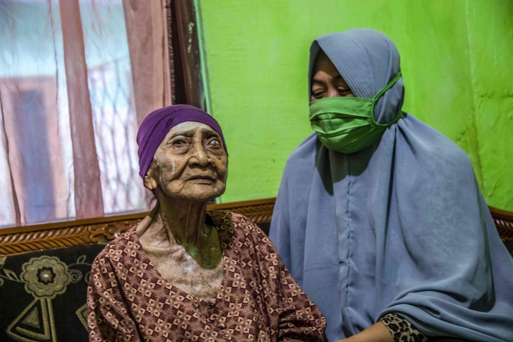 Kamtim, 100, sits in her living room with her daughter-in-law Siti Aminah in Surabaya, East Java. Photo: AFP