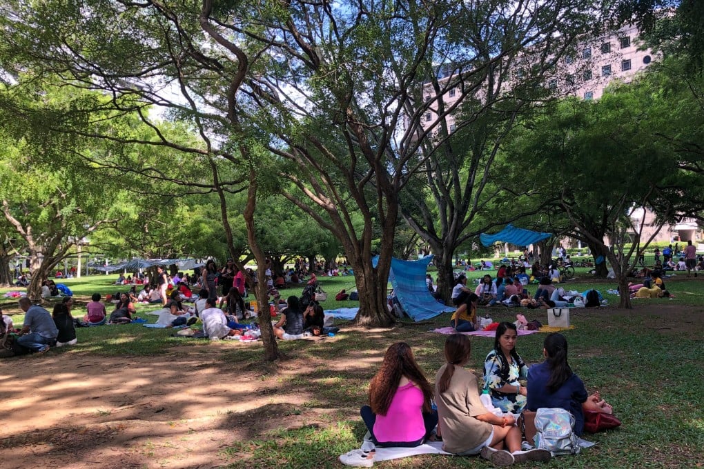 Domestic workers gather on a grass patch behind Somerset MRT Station in Singapore earlier this year. Photo: Kok Xinghui