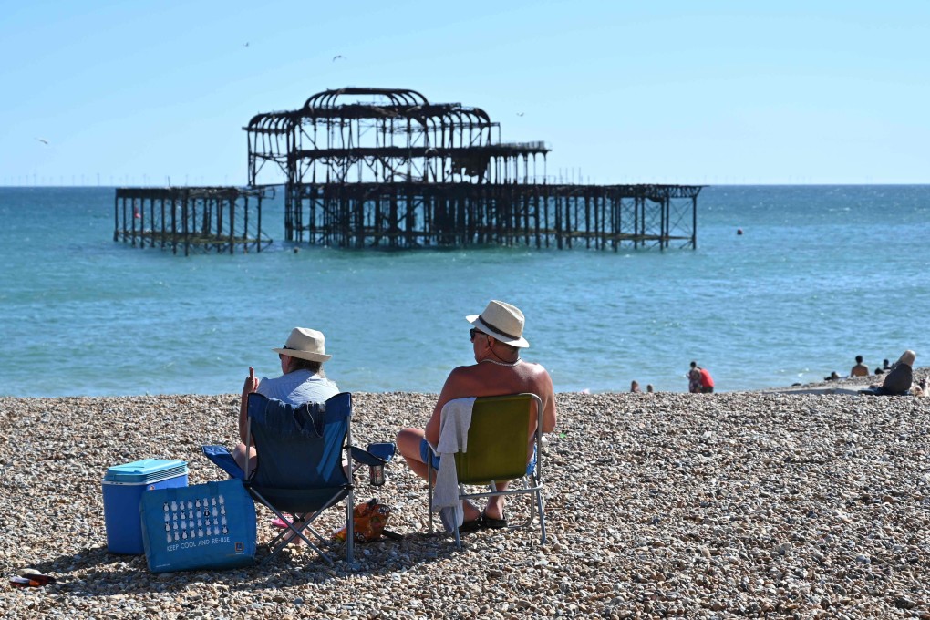 People sunbathe on the beach near the derelict West Pier in Brighton on the south coast of England. Photo: AFP