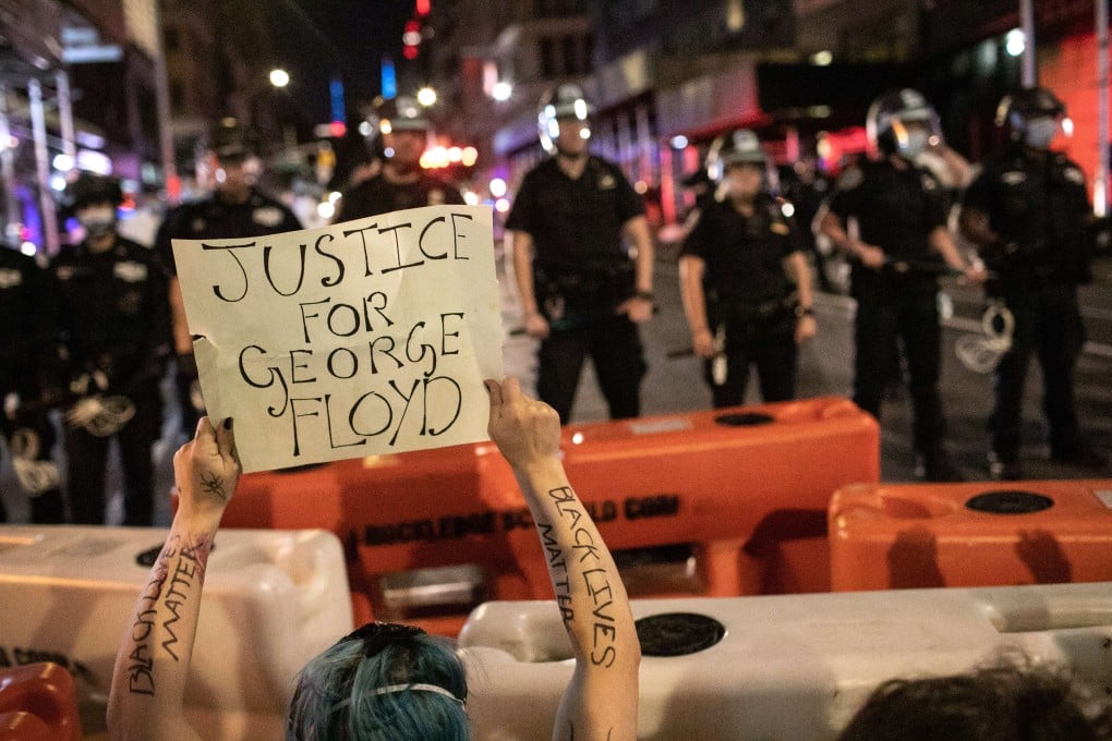 A protester holds a sign while facing off with police on Sunday in New York City. Photo: Getty Images via AFP