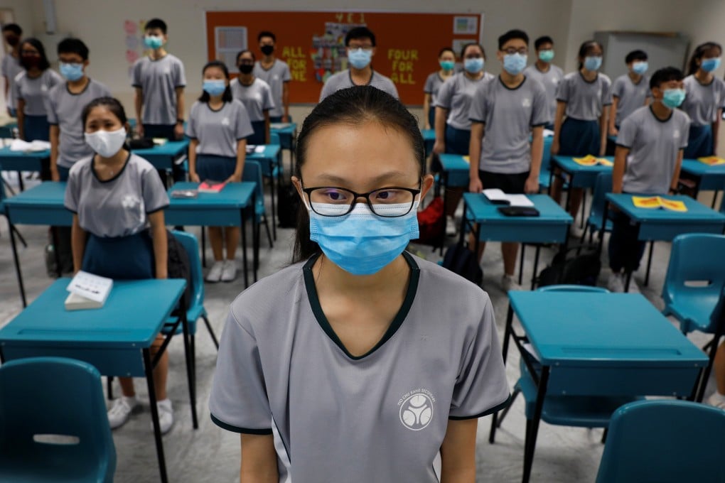 School pupils wearing face masks stand for the national anthem before classes resumed at Yio Chu Kang Secondary School, as Singapore eased its coronavirus circuit breaker restrictions. Photo: Reuters