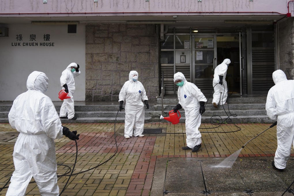 Workers wearing protective gear disinfect Luk Chuen House at Lek Yuen Estate in Sha Tin. Photo: Sam Tsang