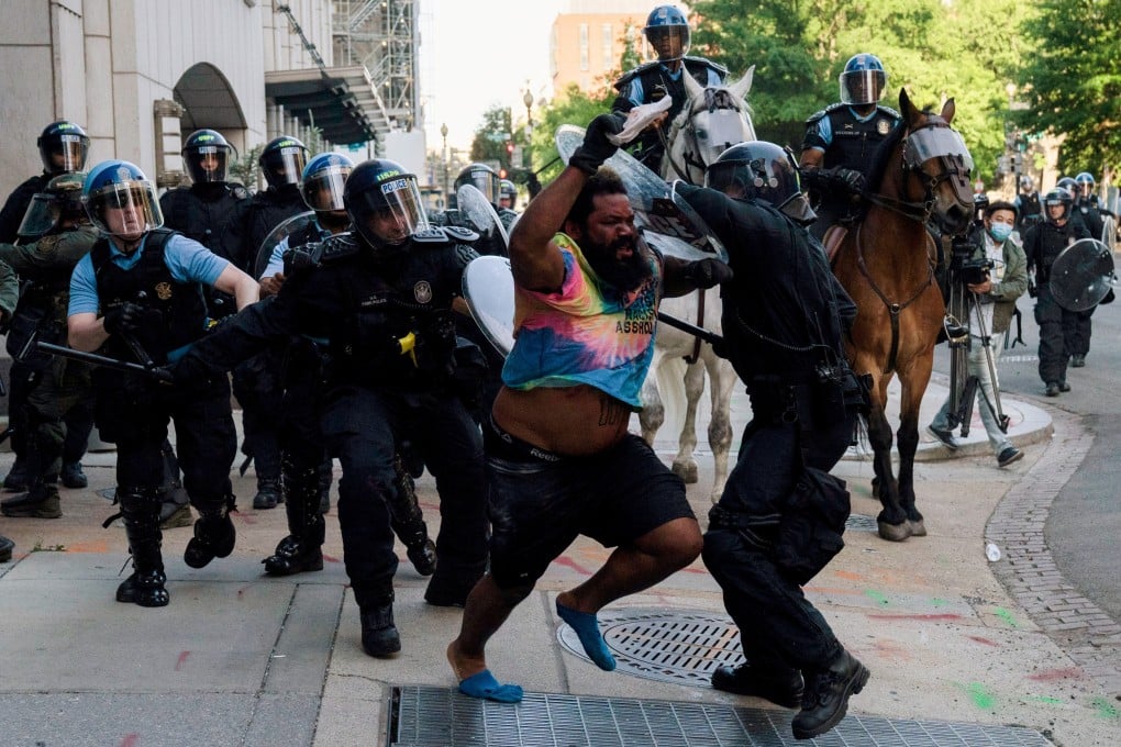 Riot police chase a man as they rush protestors to clear the area across from the White House. Photo: Reuters