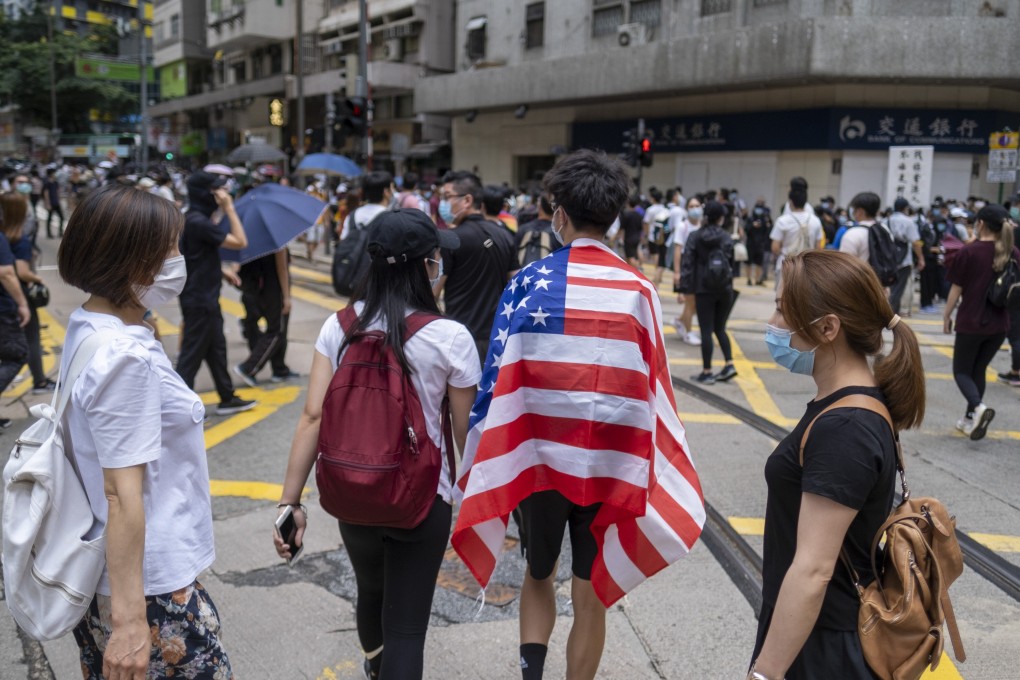 A demonstrator in Hong Kong is draped in an American flag during a protest against a planned national security law, in the city’s Wan Chai district on May 24. Photo: Bloomberg