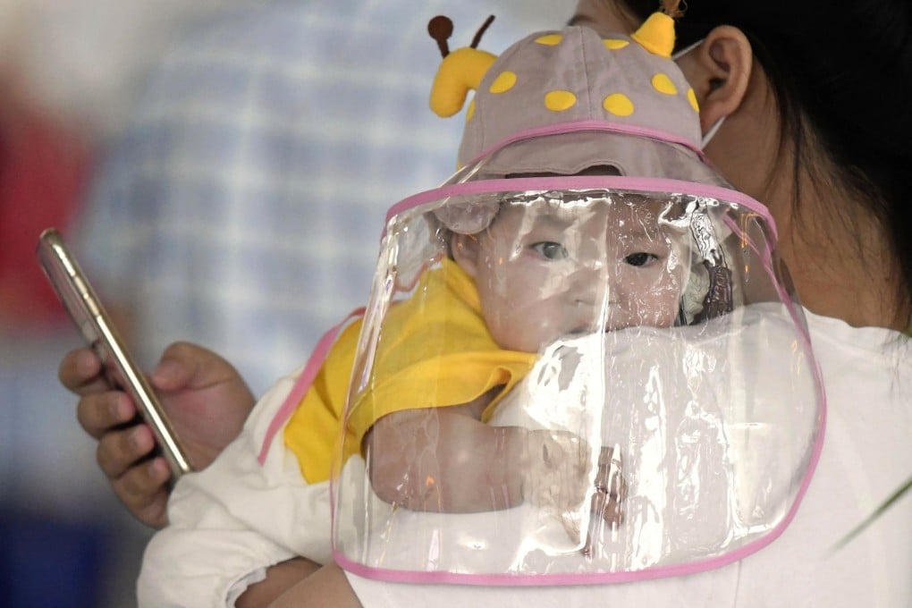 A baby with a face shield waits to board a plane at an airport in Wuhan on May 23. Photo: Kyodo News via AP