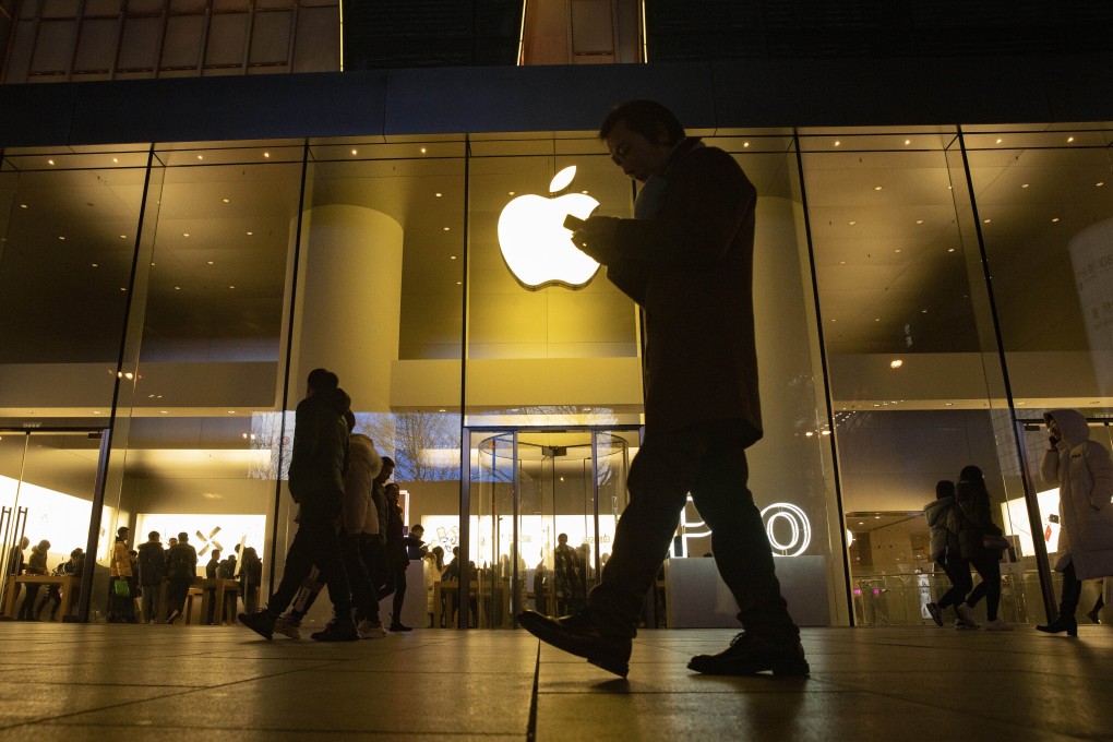 In this Dec. 13, 2019, file photo a man looks at his phone as he walks past a store of US tech giant Apple in a retail district in Beijing. Photo: AP