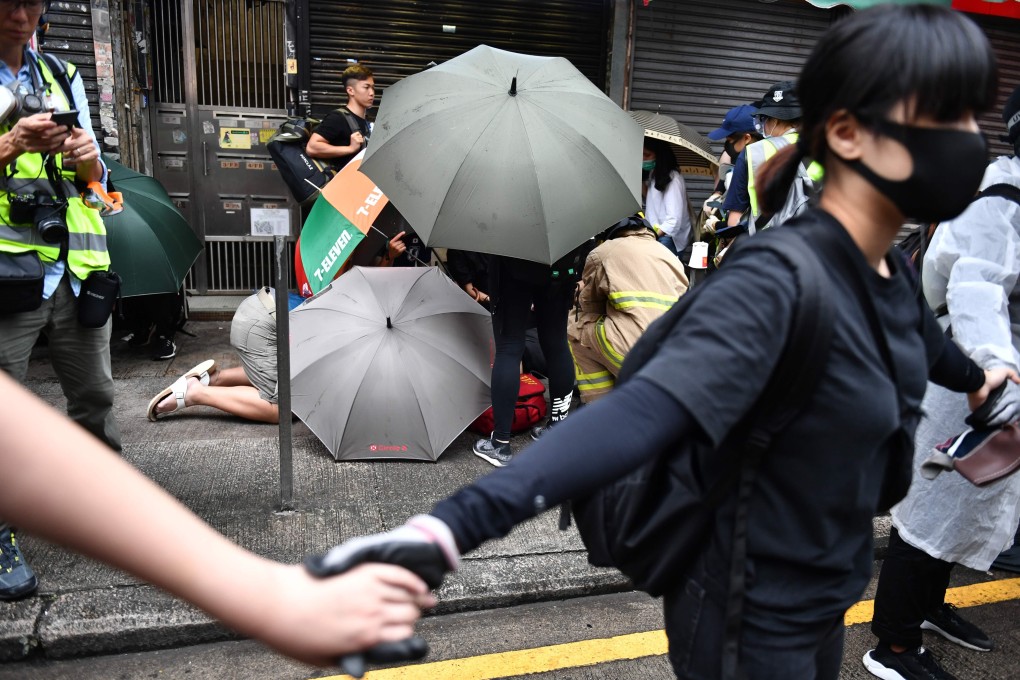 Protesters form a human chain around a fellow protester receiving medical assistance after being struck by a vehicle. Photo: AFP