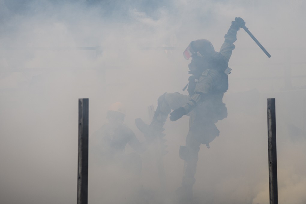 A police officer raises his baton to strike a protester who was among those attempting to escape the Hong Kong Polytechnic University campus in Hung Hom on November 18, 2019. Protesters and police clashed near the university, ending up in a nearly two-week siege of the campus. Photo: AFP