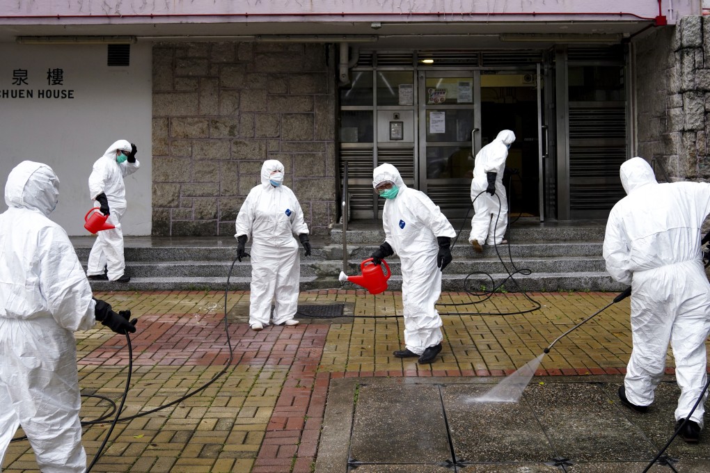 Workers wearing protective gear disinfect Luk Chuen House at Lek Yuen Estate in Sha Tin. Photo: Sam Tsang