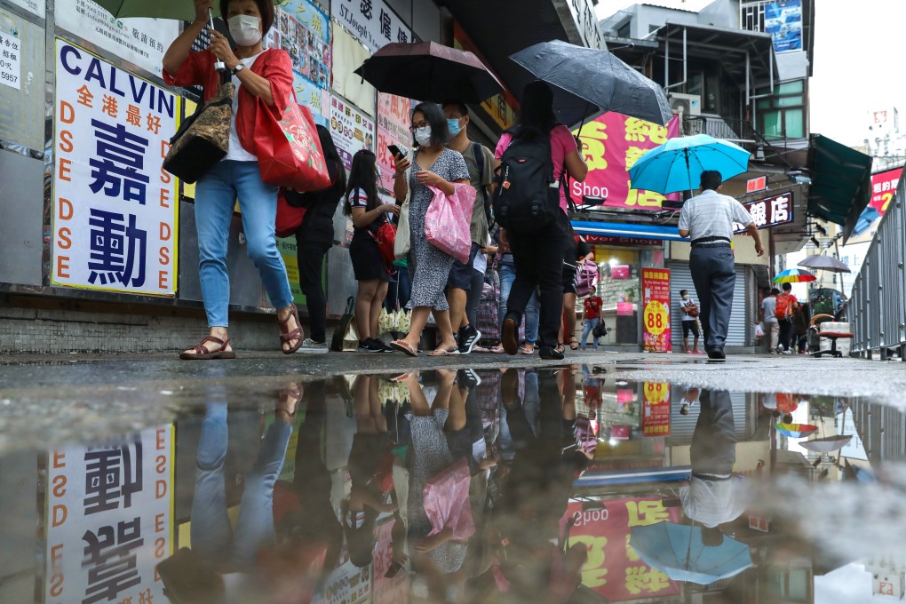 Pedestrians carrying umbrellas cross a flooded road during heavy rain in Yuen Long. Photo: K.Y. Cheng