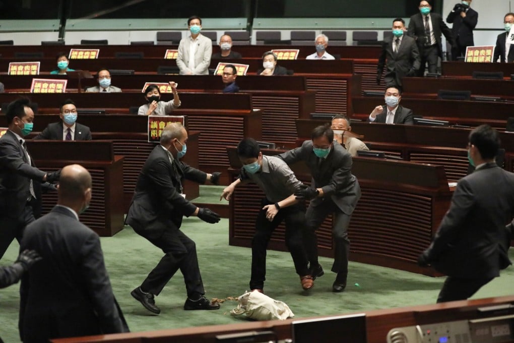 Democratic Party legislator Ted Hui is intercepted by Legco security guards as he drops a bag holding a container of foul-smelling rotten plants during the second day of the debate on the national anthem law at the Legislative Council in Tamar on May 28. Photo: Nora Tam