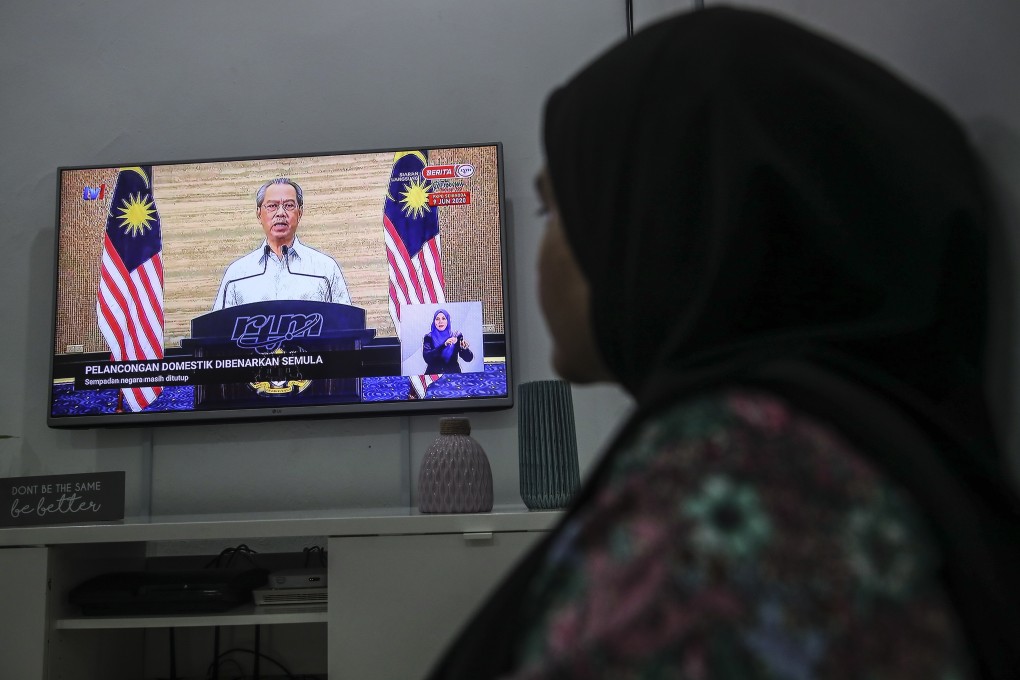 A Malaysian woman watches Prime Minister Muhyiddin Yassin on television. Photo: EPA