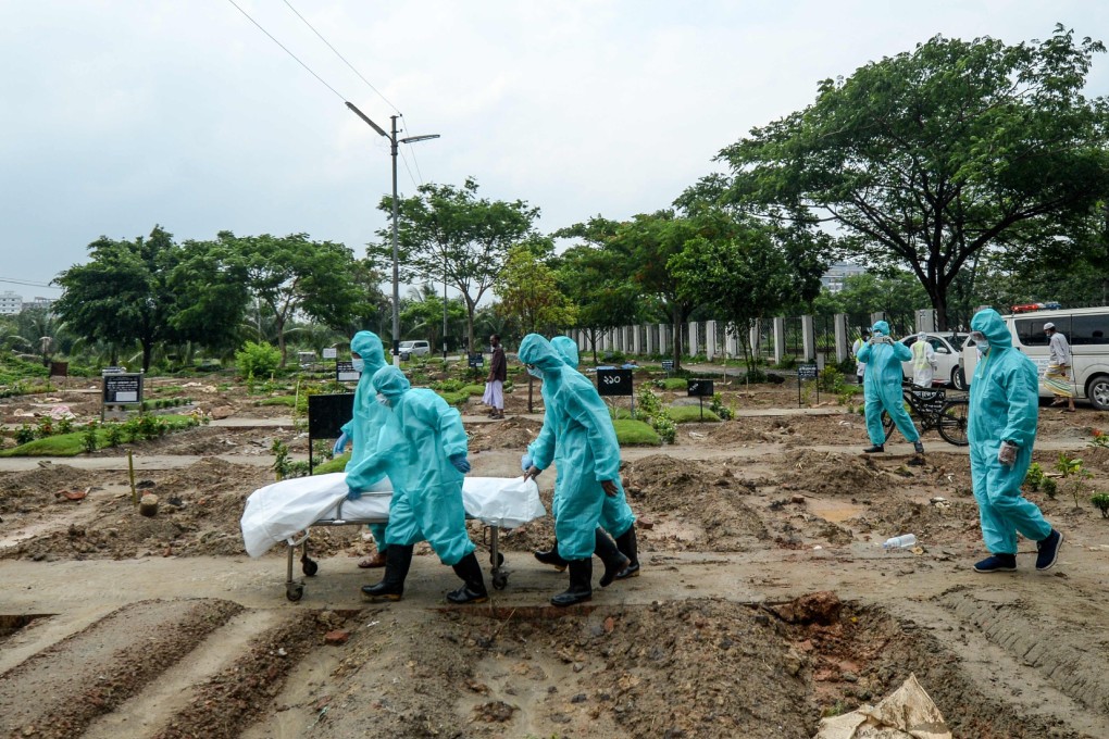 Volunteers wearing protective gear carry the body of a person who died due to the Covid-19 coronavirus during a burial in a graveyard in Dhaka. Photo: AFP
