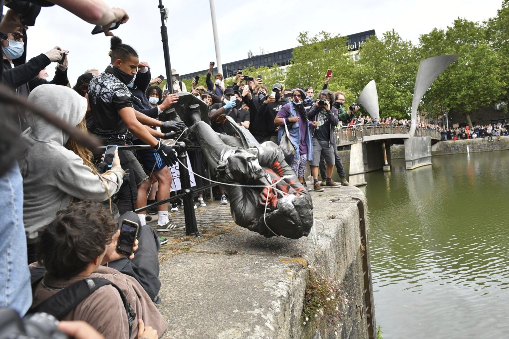 Protesters throw a statue of slave trader Edward Colston into Bristol harbour, during a Black Lives Matter protest rally, in Bristol, England. Photo: AP