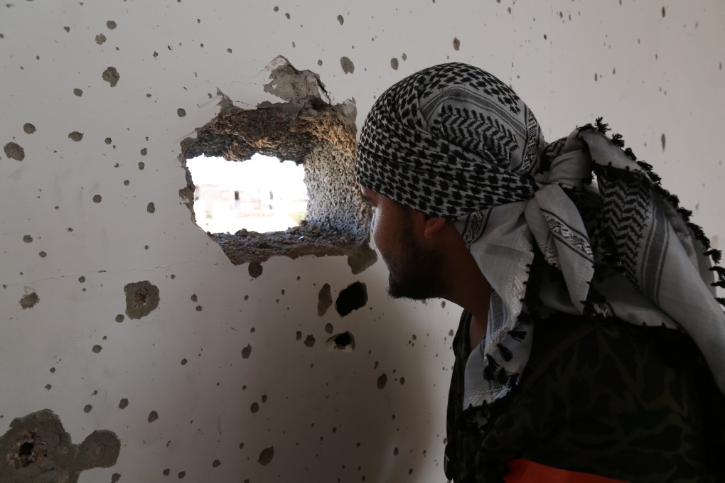 A fighter looks through a hole in the wall of Libya's central bank in Sirte during fighting in 2016. Photo: dpa