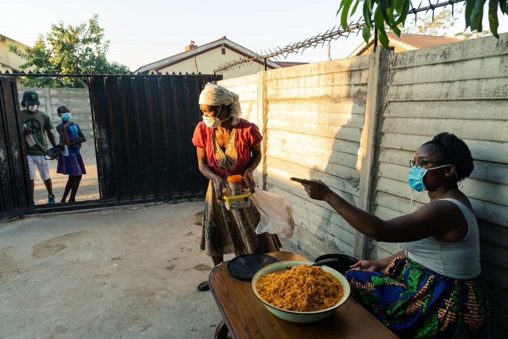Samantha Murozoki (R) hands a free meal to a woman from her home in Chitungwiza, a satellite town of Zimbabwe’s capital Harare. Photo: AFP