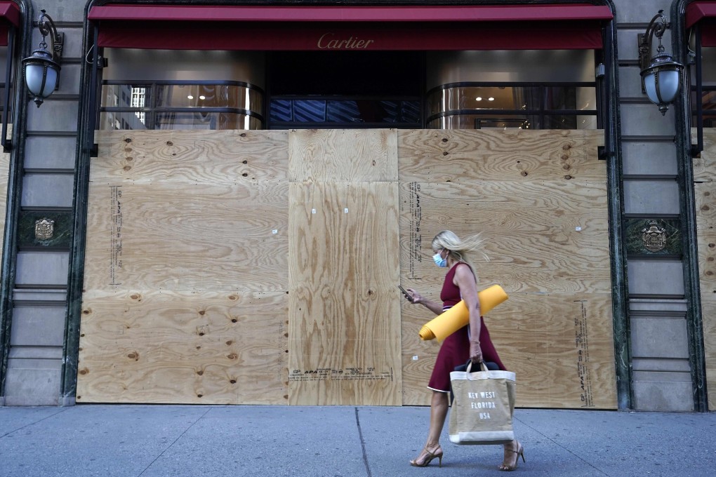 A woman walks by a boarded up Cartier store on 5th Avenue in New York on Monday. Photo: AFP